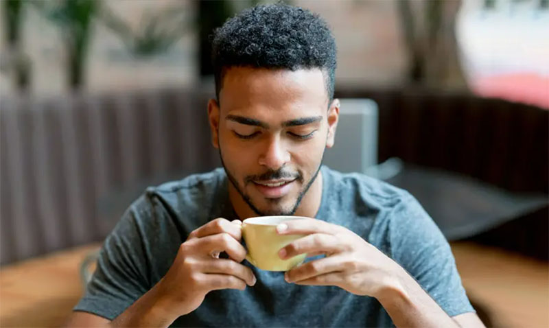 یک شخص سالم در حال نوشیدن یک فنجان قهوه